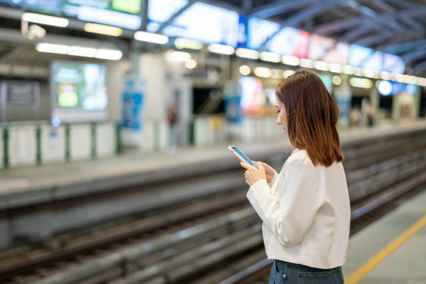 istock Young asian woman using smartphone application navigate location destination while travel by train. Asian female with cell phone standing near railway platform in train station. 2163924564