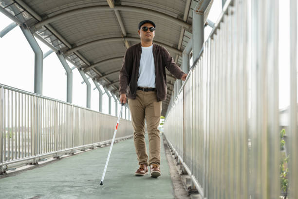 istock Young blind man walking in city with walking stick. Visually impaired man difficult to traveling on the road wearing sun glasses Cross the road cross the footbridge 2163925004