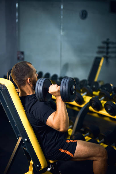 istock Middle age man with dumbbells flexing muscles in gym 2163927129