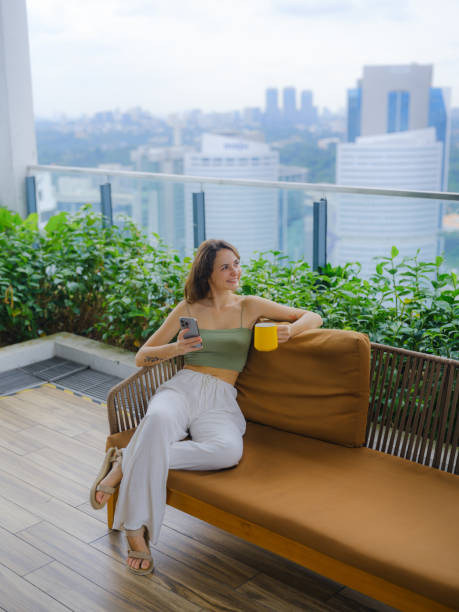 istock Woman using smartphone drinking coffee on rooftop garden 2163927183