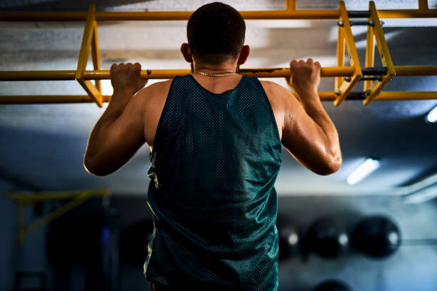 istock Back view of a strong man doing pull ups in a gym 2163927225