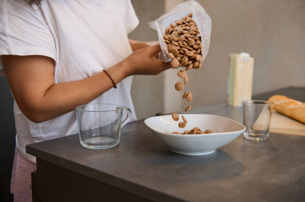 istock Person pouring cereal into a bowl in a cozy kitchen setting 2163929196