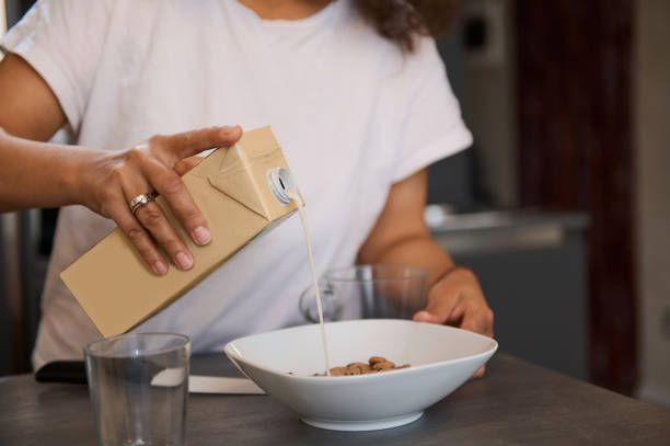 Person pouring milk into cereal bowl for breakfast in a cozy kitchen setting
