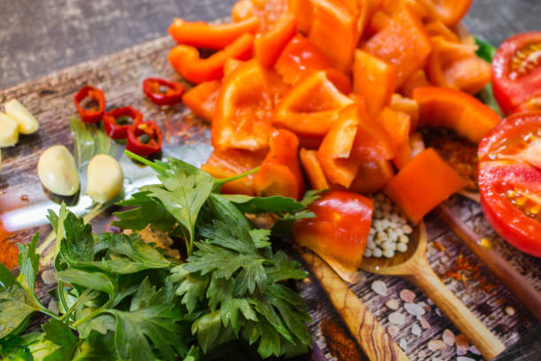 Vegetables and herbs on cutting board. Sliced tomato, bell pepper, chilli pepper, garlic and parsley on the table. Summer salad ingredients. Healthy eating. Organic food background.