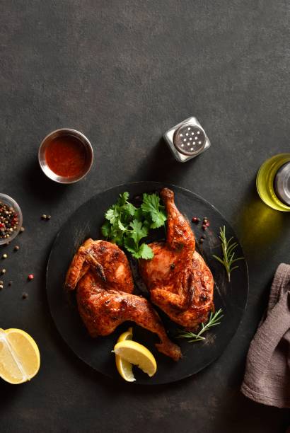 istock Roasted half chicken on black wooden platter over dark stone background 2163933068