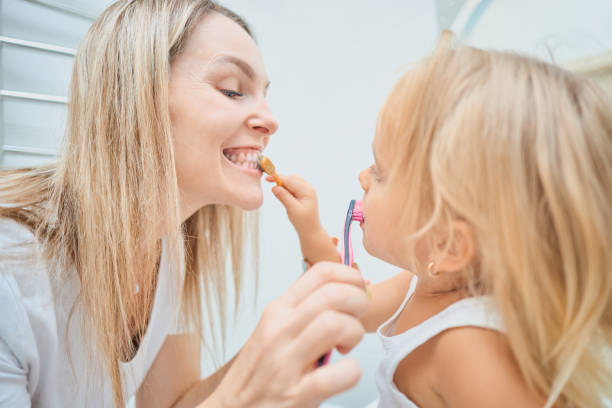 istock Woman and child brushing each other's teeth 2163933172