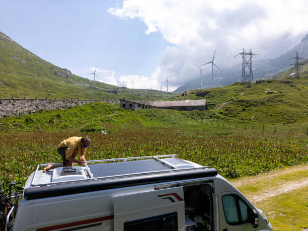 istock Man Adjusting Solar Panels on Camper Van Roof in Mountainous Area 2163940421