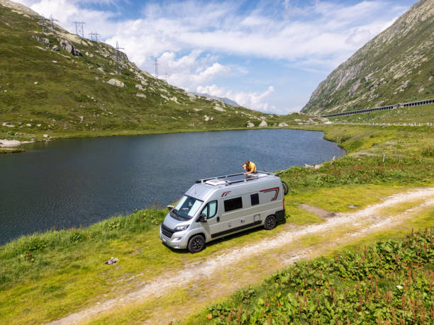 istock Man Adjusting Solar Panels on Camper Van by Mountain Lake 2163940559