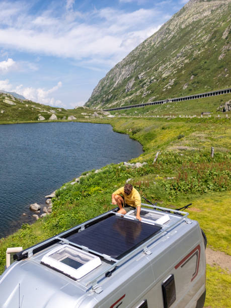 istock Man Working on Solar Panels on Camper Van Roof by Lake 2163940638