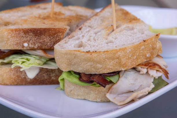 istock A turkey sandwich with bacon and lettuce is on a white plate 2163941857