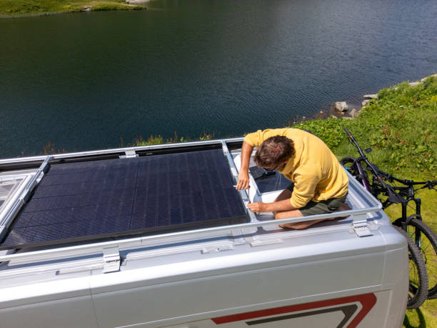 istock Man Installing Solar Panels on Van in Mountainous Landscape 2163943043