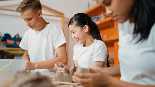 istock Handsome student dipping hand in to water to soften clay at class. Edification. 2163950456