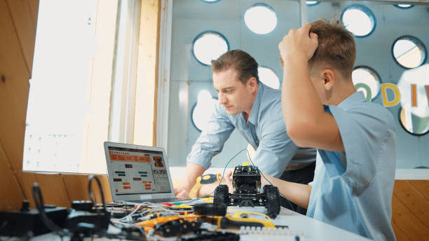 istock Teacher help student fixing car model and giving advise at class. Edification. 2163951614