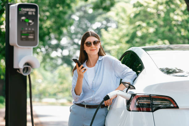 istock Young woman using smartphone to pay for electric car charging. Exalt 2163965151