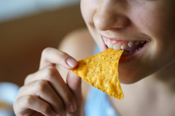 istock Anonymous girl smiling while eating spicy Mexican tortilla chip 2163965349