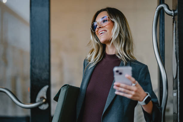 istock Businesswoman Smiling Outdoors While Holding Smartphone 2163968638