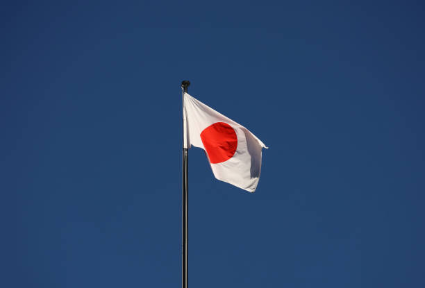 istock Japanese flag waving in the wind against a blue sky 2163970167