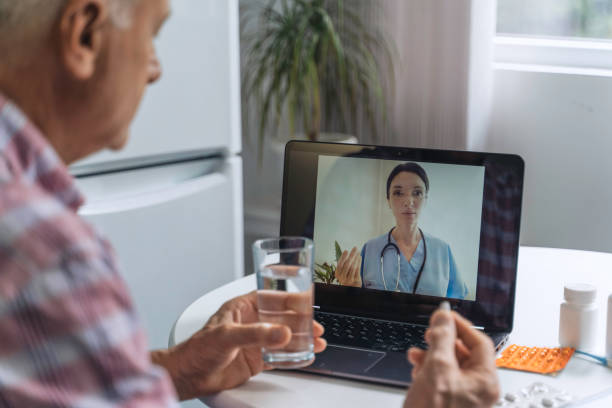 istock Older man takes medication, consults doctor virtually 2163971915