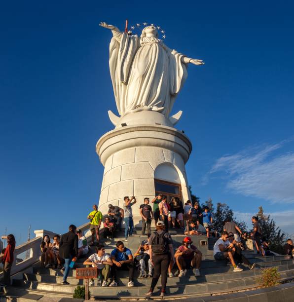 Santiago, Chile - March 24, 2023: Tourist People Group Sitting on Stairs by Famous Virgin Mary Monument Statue On Cerro San Cristobal Hill. Foreground Sign reads Silence
