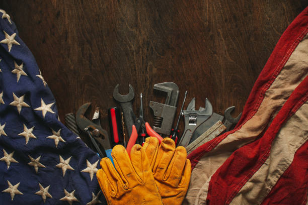 Worn work gloves on tools with US American flag. Made in USA, American workforce, blue collar worker, or Labor Day concept.