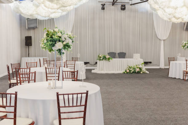 istock Decorated interior for festive event. Fancy table set for dinner with white flower composition in restaurant, luxury interior background. Wedding elegant banquet decoration arranged by catering service. 2163973799