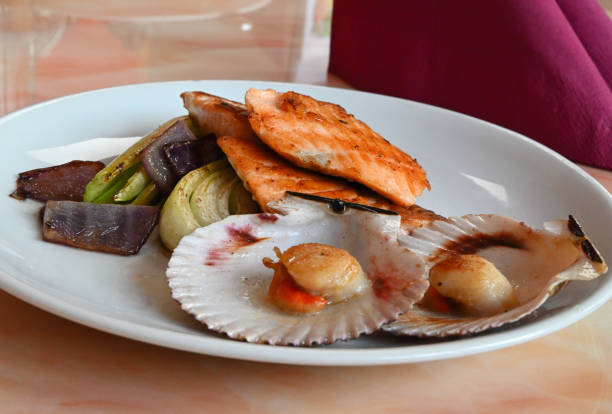 scallops and grilled salmon with leek served on white plate