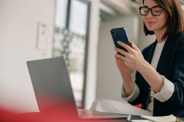 istock A confident businesswoman is using a smartphone and laptop in a modern office setting 2163975341