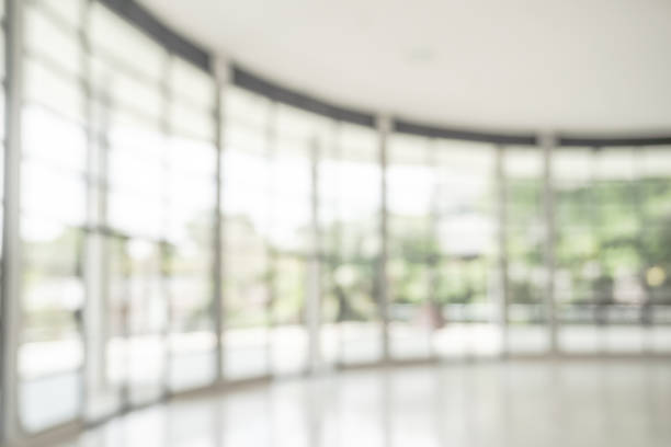 istock Office building lobby hall blur background or blurry school hallway corridor interior view looking toward empty corridor entrance, glass curtain wall and floor with exterior light illumination 2163983198