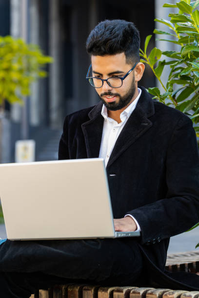 istock Happy Indian businessman typing working remote on wireless laptop computer browsing online outdoors 2163985084