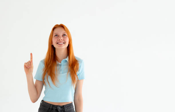 istock Smiling woman pointing finger up over white background 2163989136