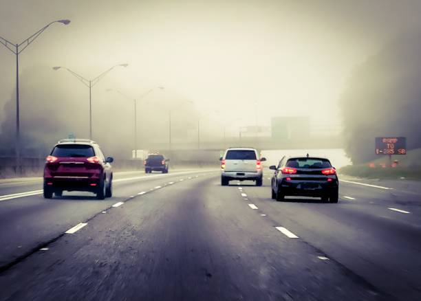 Poor visibility at night during winter fog .  City traffic moving slowly through a foggy evening.