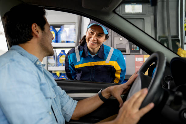 istock Gas station attendant talking to a client while refueling his car 2163991740