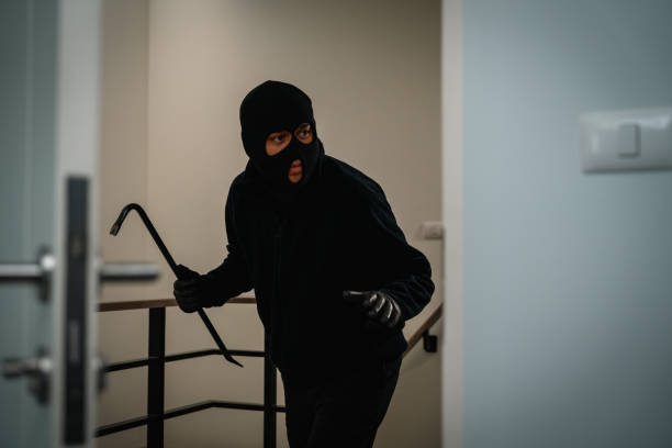 istock Thief in uniform black jacket various action housebreak. The Robber terrorism criminal escapes with balaclava and crowbar entering a house for stealing Housebreak at night 2163998241