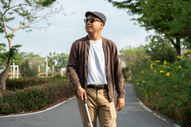 istock Young blind man walking in city with walking stick. Visually impaired man difficult to traveling on the road wearing sun glasses Cross the road cross the footbridge 2163998361