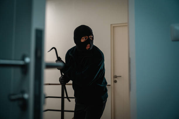 istock Thief in uniform black jacket various action housebreak. The Robber terrorism criminal escapes with balaclava and crowbar entering a house for stealing Housebreak at night 2163998371