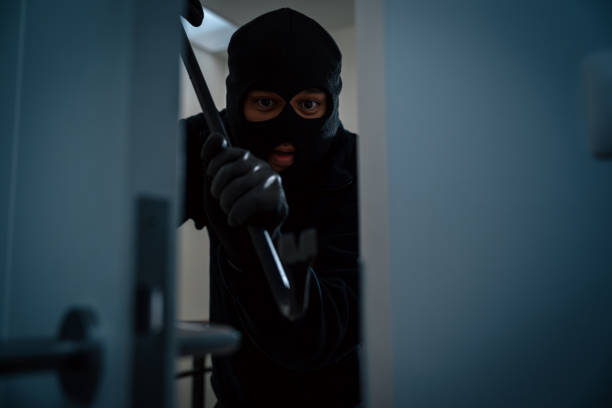 istock Thief in uniform black jacket various action housebreak. The Robber terrorism criminal escapes with balaclava and crowbar entering a house for stealing Housebreak at night 2163998497