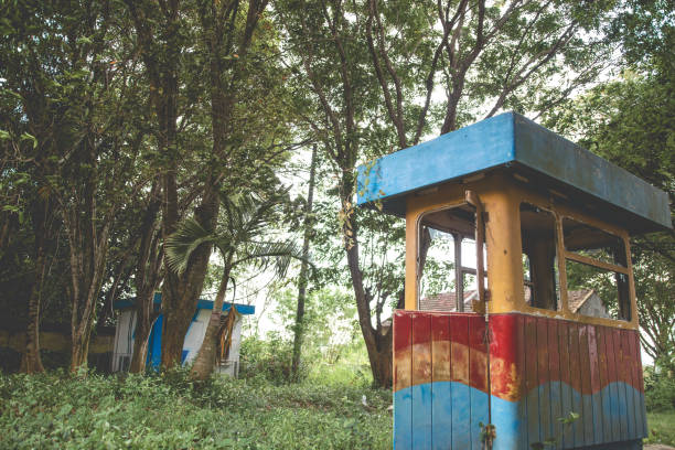 Abandoned old building with overgrown grass surrounding. Abandoned parking booth building.