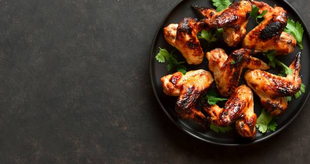 istock Bbq chicken wings on plate over dark stone background 2164006949