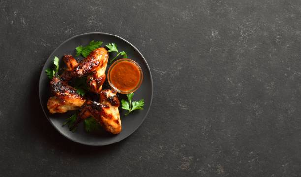 istock Bbq chicken wings on plate over dark stone background with copy space 2164006958