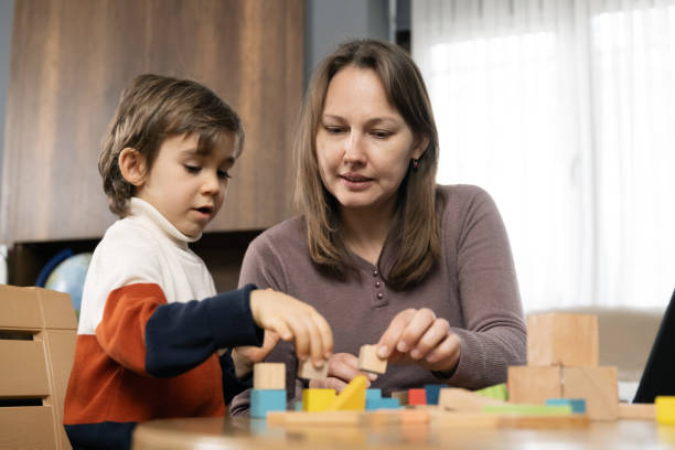 istock Little child boy playing with toy blocks while his mother working at home 2164007624