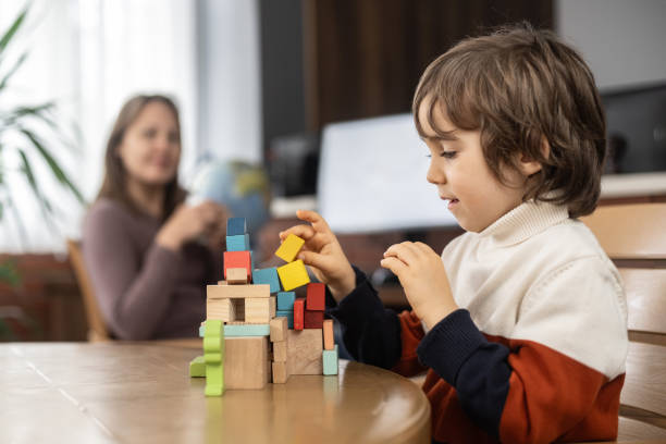 istock Little child boy playing with toy blocks while his mother working at home 2164008035