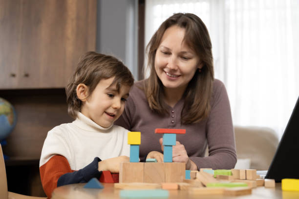 istock Little child boy playing with toy blocks while his mother working at home 2164008307