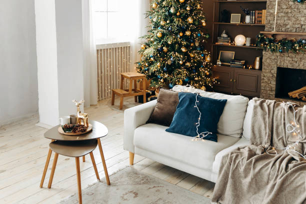 istock Sofa with pillows and a plaid on a blurred background with a Christmas tree and a fireplace in the interior of a cozy living room with large windows and brown walls 2164013486