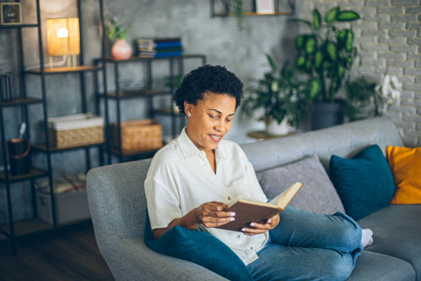 istock Woman relaxing at home reading a book lying on sofa 2164015556