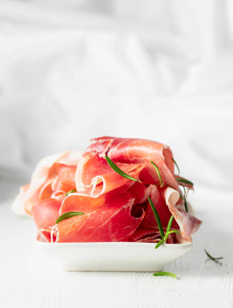 istock Prosciutto with rosemary on a white wooden table. 2164015719