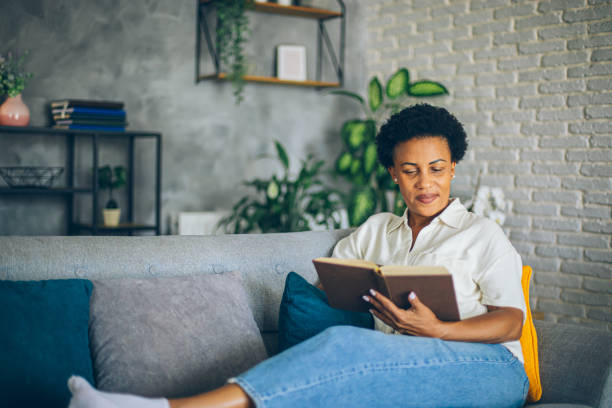 istock Woman relaxing at home reading a book lying on sofa 2164015814