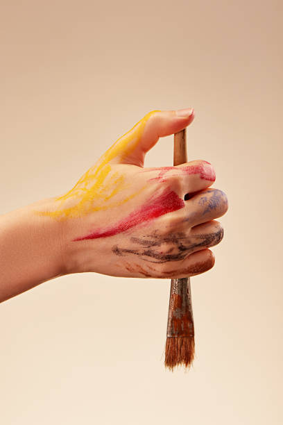istock Woman's hand with gouache marks holding brush on light background 2164017710
