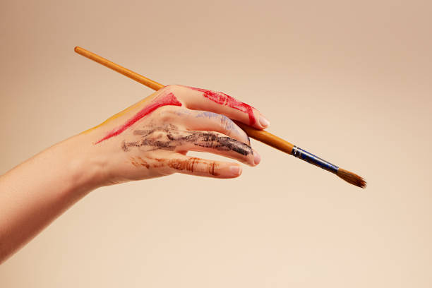 istock Woman's hand with gouache marks holding brush on light background 2164017717