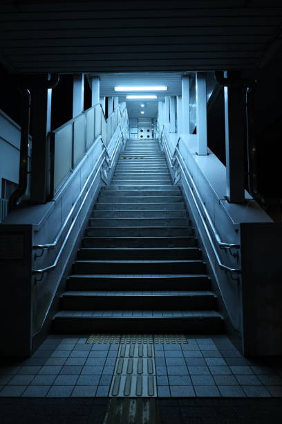 A dark and eerie staircase leading to the Sunadabashi bus and subway station in Nagoya. The lighting and atmosphere evoke a sense of horror, capturing the unsettling ambiance of this urban transit spot.