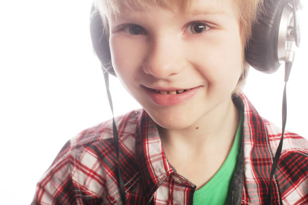 Happy little boy with headphones waving during a video call at home and looking at camera.
